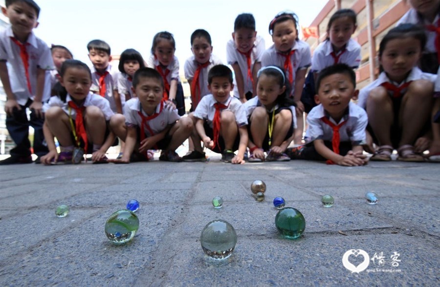 2017年5月31日,河北省邯郸市丛台小学的学生玩弹玻璃球游戏。