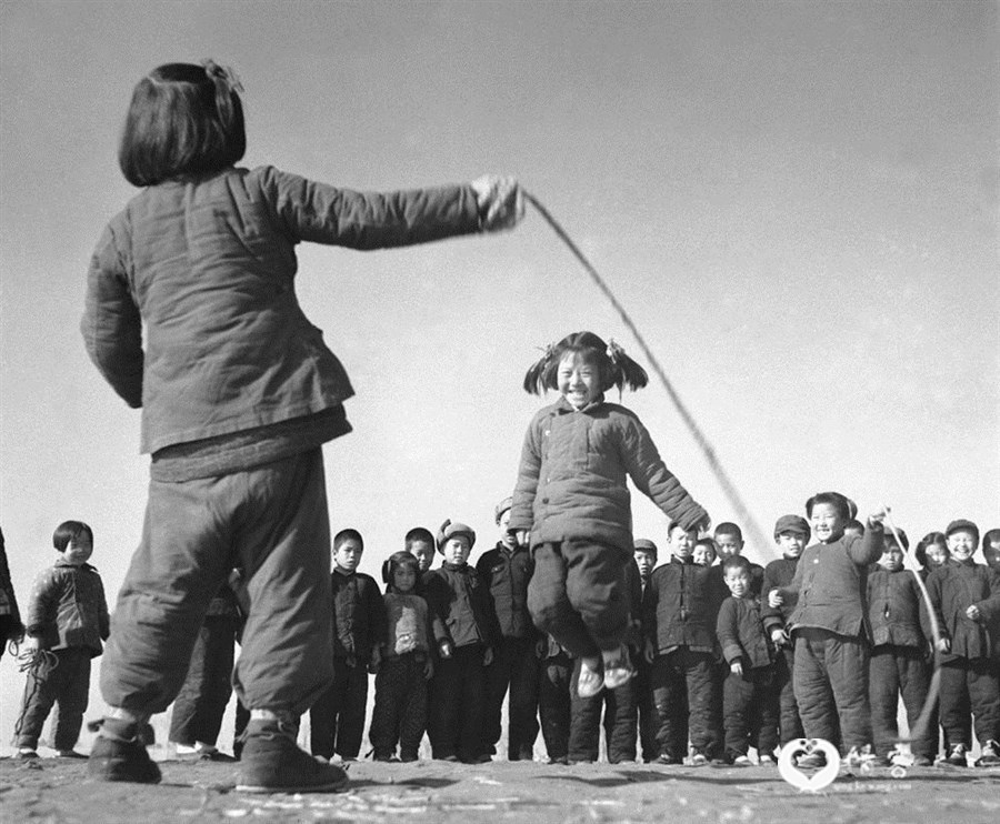 1956年12月,河北省高阳县邢果庄村的小学生们在空地上跳绳。